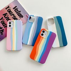 three phone cases with rainbow stripes on them next to a notepad and pencils