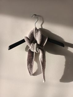 a knitted scarf hanging from a hook on a white wall next to a pair of scissors