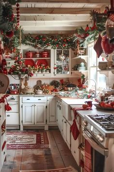 a kitchen decorated for christmas with red and green garlands on the ceiling, white cabinets and appliances