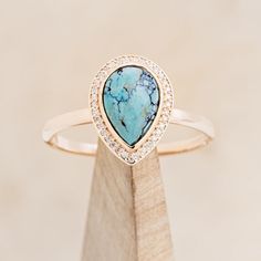 a ring with a blue stone surrounded by white and clear stones on top of a wooden stand