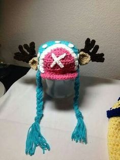 a crocheted hat with moose antlers on it sitting next to a cup