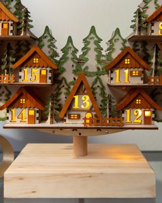 a wooden table topped with lots of small houses covered in christmas trees and numbers on them