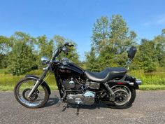 a black motorcycle parked on the side of a road next to some grass and trees