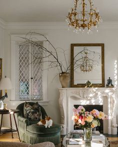 a living room filled with furniture and a chandelier above a fire place in front of a fireplace