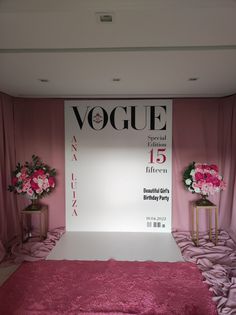 a pink carpeted area with two vases and flowers on the floor in front of a sign