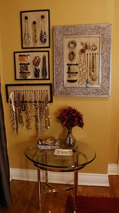 there is a glass table in the room with jewelry on it and pictures hanging on the wall