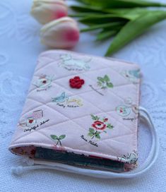 a pink wallet with flowers on it next to a tulip