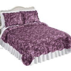 a bed with a purple bedspread and white headboard on top of it