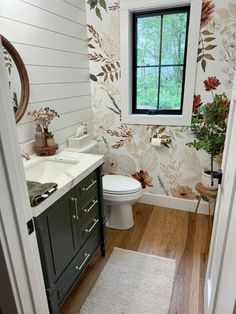 a bathroom with floral wallpaper and wooden floors