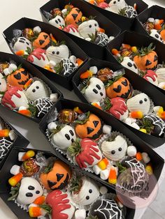 there are many halloween themed treats in the black boxes on the table with white and orange decorations