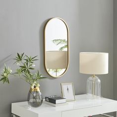 a white table topped with a vase filled with flowers and a mirror on the wall