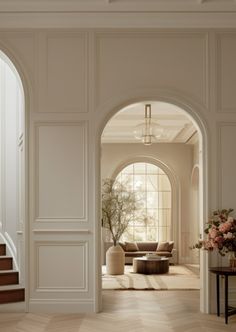 an open doorway leading to a living room with white walls and wood floors, along with a staircase that leads up to the second floor