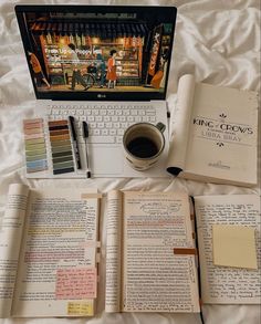 an open book sitting next to a laptop computer on top of a bed