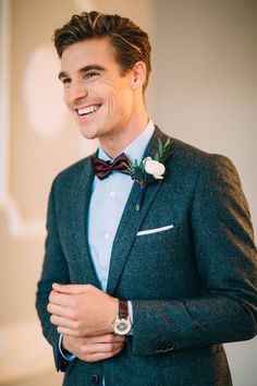 a man in a suit and bow tie smiles at the camera while wearing a watch