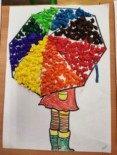 a child's drawing of a girl holding an umbrella made out of colored pebbles