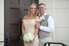 a man and woman standing in front of a door holding bouquets of white flowers