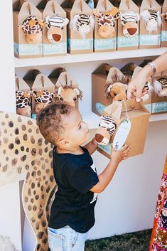 a little boy that is standing in front of a shelf with stuffed animals on it