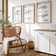 three framed pictures hang on the wall next to a wicker chair and sideboard