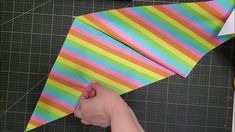 someone is holding a colorful paper airplane on a cutting board