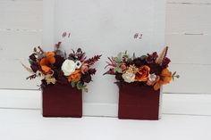 two red vases with flowers on them are sitting side by side against a white wall