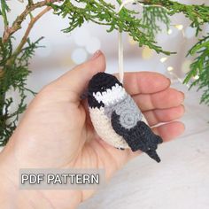 a hand holding a small crocheted bird ornament on a tree branch