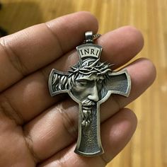 a person holding a metal cross with jesus on it's face in their hand