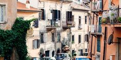 cars are parked on the side of an alleyway in europe with balconies