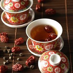 two cups and saucers filled with tea sit on a table next to dried raisins