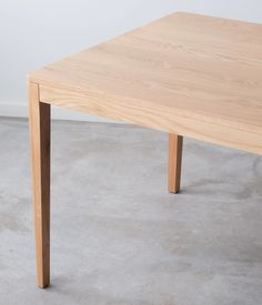 a wooden table sitting on top of a cement floor next to a white wall in an empty room