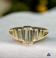 an image of a gold ring with three emerald cut diamonds on the sides and four baguettes in the middle