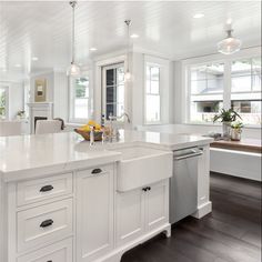 a large white kitchen with an island in the middle