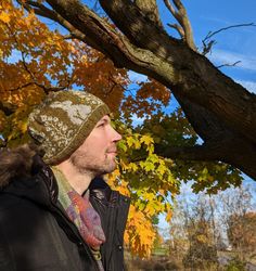 a man standing under a tree in the fall