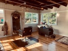 a living room filled with furniture and windows next to a wooden floor covered in sunlight