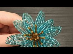 a hand holding a blue beaded flower brooch