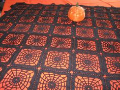 an orange vase sitting on top of a black crocheted tablecloth with circles