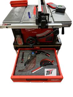 a red table saw with tools in it