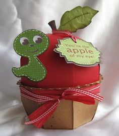 an apple is wrapped in paper and has a green worm on it's side