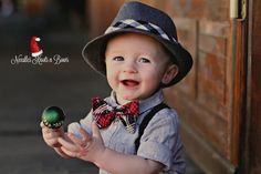 a young boy wearing a hat and bow tie holding an egg