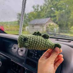 someone is holding up a crocheted alligator keychain in their car window