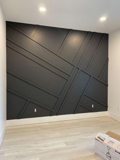 an empty room with some boxes on the floor and a wall painted in dark gray