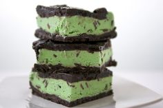 three pieces of cake sitting on top of a white plate with green frosting and oreo cookies