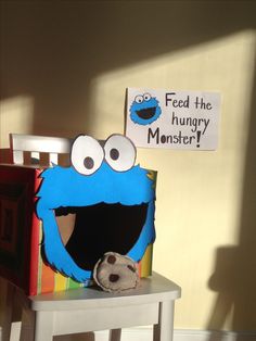 a stuffed animal sitting on top of a wooden chair next to a sign that says feed the hungry monster