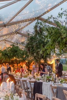 A clear marquee pictured at dusk, dressed for a wedding.   With a canopy of fairy lights,   long banquet tables with soft pretty florals and lots of candlelight. Colourful Marquee Wedding, Garden Wedding Marquee, Marquee Garden Party, Clear Span Marquee Wedding, Rustic Wedding Marquee, Clearspan Marquee Wedding, Wedding Marquee Flowers, Marquee Fairy Lights, Wedding Marquee Decoration