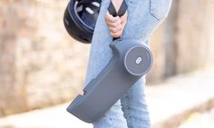 a woman holding an exercise device in her right hand while walking down the street with one foot on it