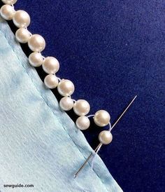 a close up of a piece of cloth with pearls on it and a needle in the middle