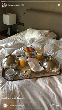 a tray with food and drinks on top of a bed