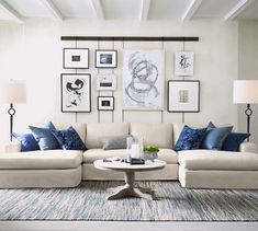 a living room with white couches and blue throw pillows on the wall above them