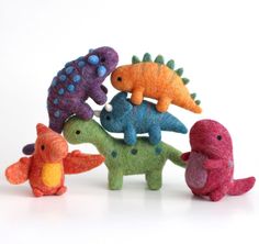 several small stuffed animals are arranged in a row on a white surface with one toy dinosaur