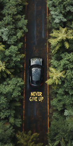 an aerial view of a car parked in the middle of a road surrounded by trees