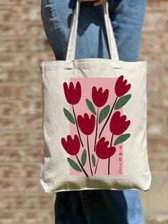 a woman holding a pink bag with red flowers on it